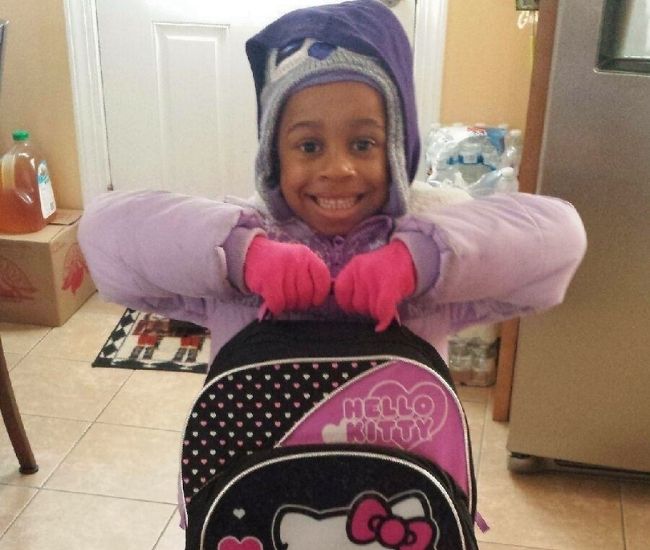 Gabrielle Eileen White in winter clothing holding a black and pink Hello Kitty backpack in a hallway